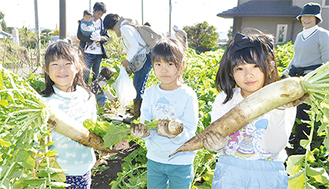 収穫物を手に笑顔の子どもたち