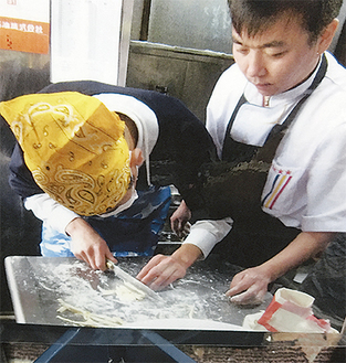 厨房で教わりながら食材を切る作業を体験する生徒