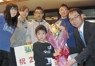 宮村副市長（右）から花束を受け取る野場さん家族