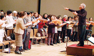 指揮者の小泉さんと真剣に練習する合唱団