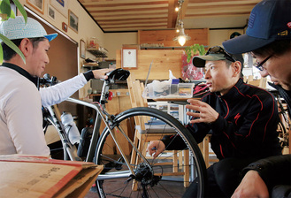自転車のメンテナンスを説明する中川さん（右奥）