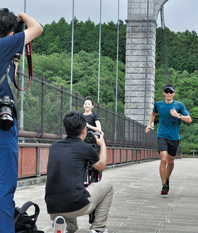 風の吊り橋で撮影に参加する青山さん（右）