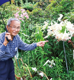 自宅の庭に咲く花の塊を説明する杉崎さん