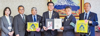 黄色いランドセルカバーなどを寄贈した古谷会長（右から２番目）と高橋市長（中央）