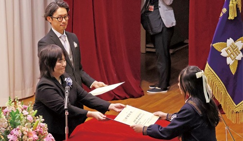 木の紙の卒業証書を受け取る卒業生