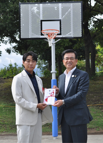 寄贈したゴールの前で高橋市長に目録を手渡す鈴木社長（左）