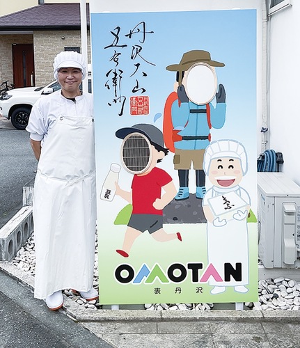 顔出しパネルの横に立つ福田さん