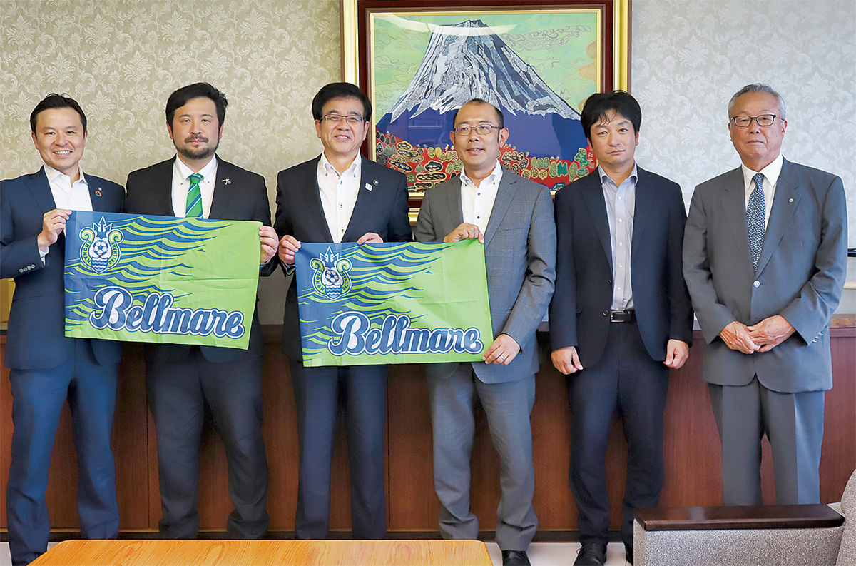 古川社長(左)や奥村監督(左から2番目)が高橋市長にチームのフラッグを手渡し、試合に向け抱負を語った