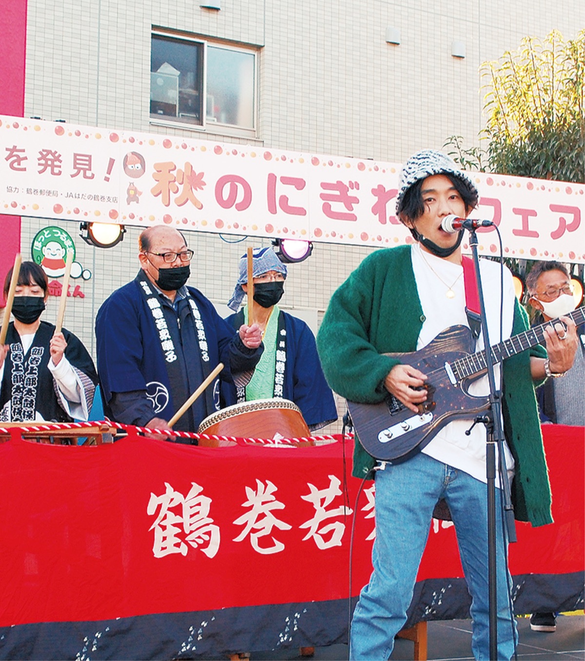 ギターのバックで太鼓を叩く保存会のメンバー