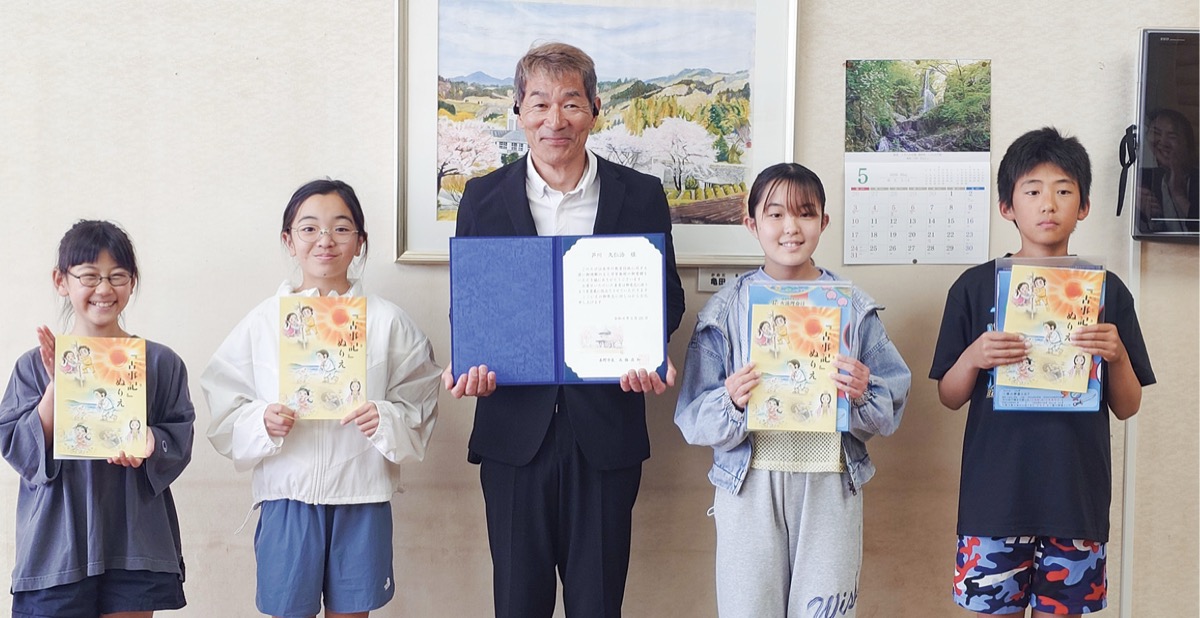 教材を受け取った児童と芦川さん(中央)