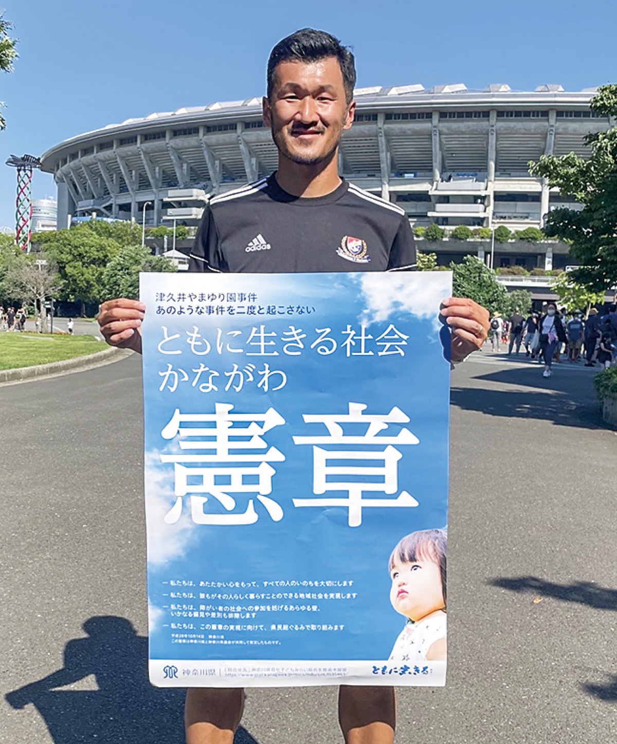 憲章ポスターを持つ横浜市出身で元F・マリノス選手の富澤清太郎コーチ